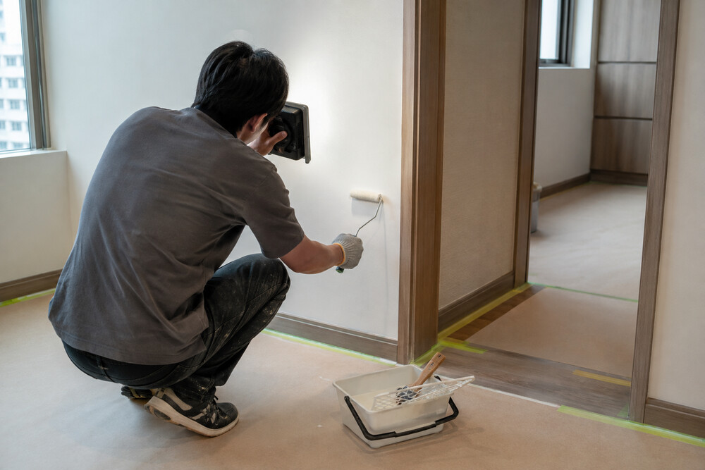 高雄住宅裝修收尾階段，施工人員以工作燈檢查牆面並進行局部補漆與門框收邊
